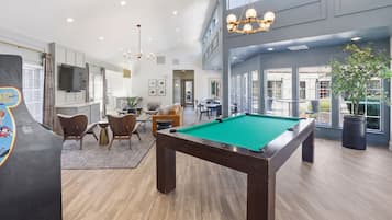 A spacious indoor area with a pool table, seating, and a large window providing a view.
