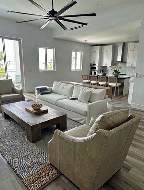 A modern living room with a sofa, a coffee table, and a ceiling fan. - New Luxury Key Colony Beach 5BR | Pool + 40' Dock (Key Colony Beach)