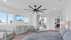 A spacious bedroom with a large bed, a ceiling fan, and a view of the beach through the window. - New Luxury Key Colony Beach 5BR | Pool + 40' Dock (Key Colony Beach)