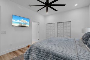 A bedroom with a bed, a ceiling fan, a TV on the wall, and a closet with sliding doors. - New Luxury Key Colony Beach 5BR | Pool + 40' Dock (Key Colony Beach)