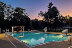 Ein Schwimmbecken mit überdachtem Bereich und Liegestühlen.