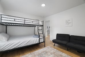 Ein Stockbett mit Matratze und Kissen, eine schwarze Couch, ein Teppich und ein motivierender Poster an der Wand.