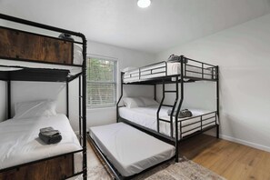 Ein Zimmer mit zwei Etagenbetten, einem Fenster mit Jalousien und Holzboden.
