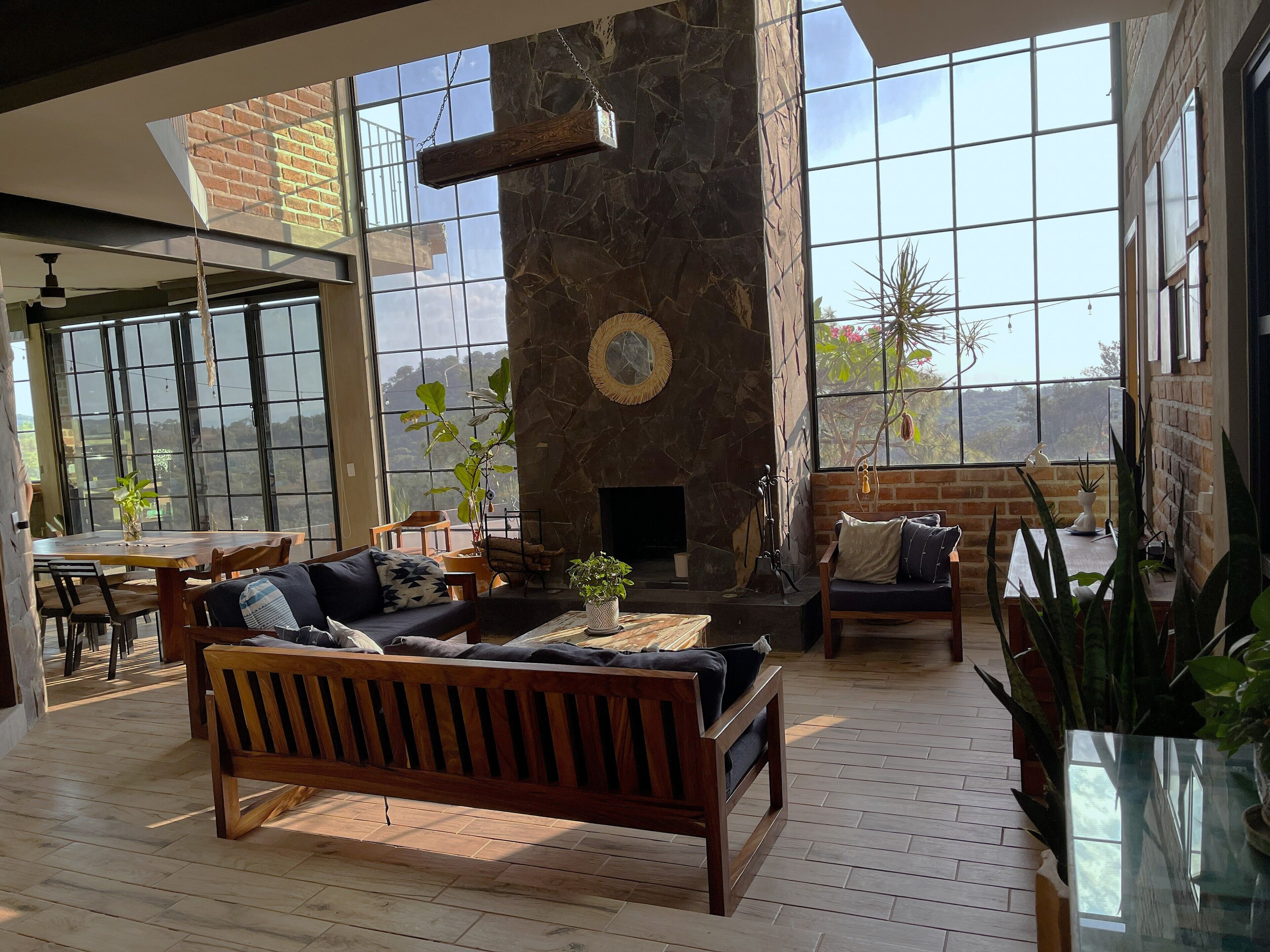 A spacious living area with a stone fireplace, large windows, and a wooden bench.