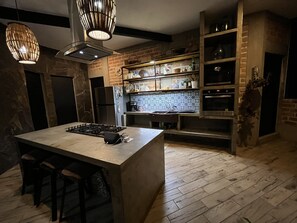 A modern kitchen with a central island, built-in appliances, and a brick backsplash.