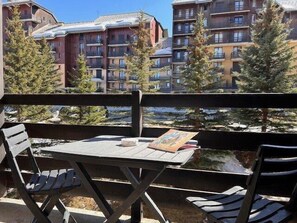 A balcony with a table and chairs, overlooking a building with multiple balconies and trees. - 50m from ski slopes, 2nd floor, balcony, tv, ski locker, 19m², Risoul (Risoul)