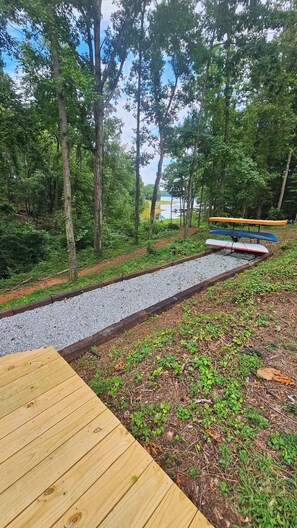 A wooden deck with a gravel path leading to a body of water, surrounded by trees. - The Cove at Portman, near Clemson. (Anderson)
