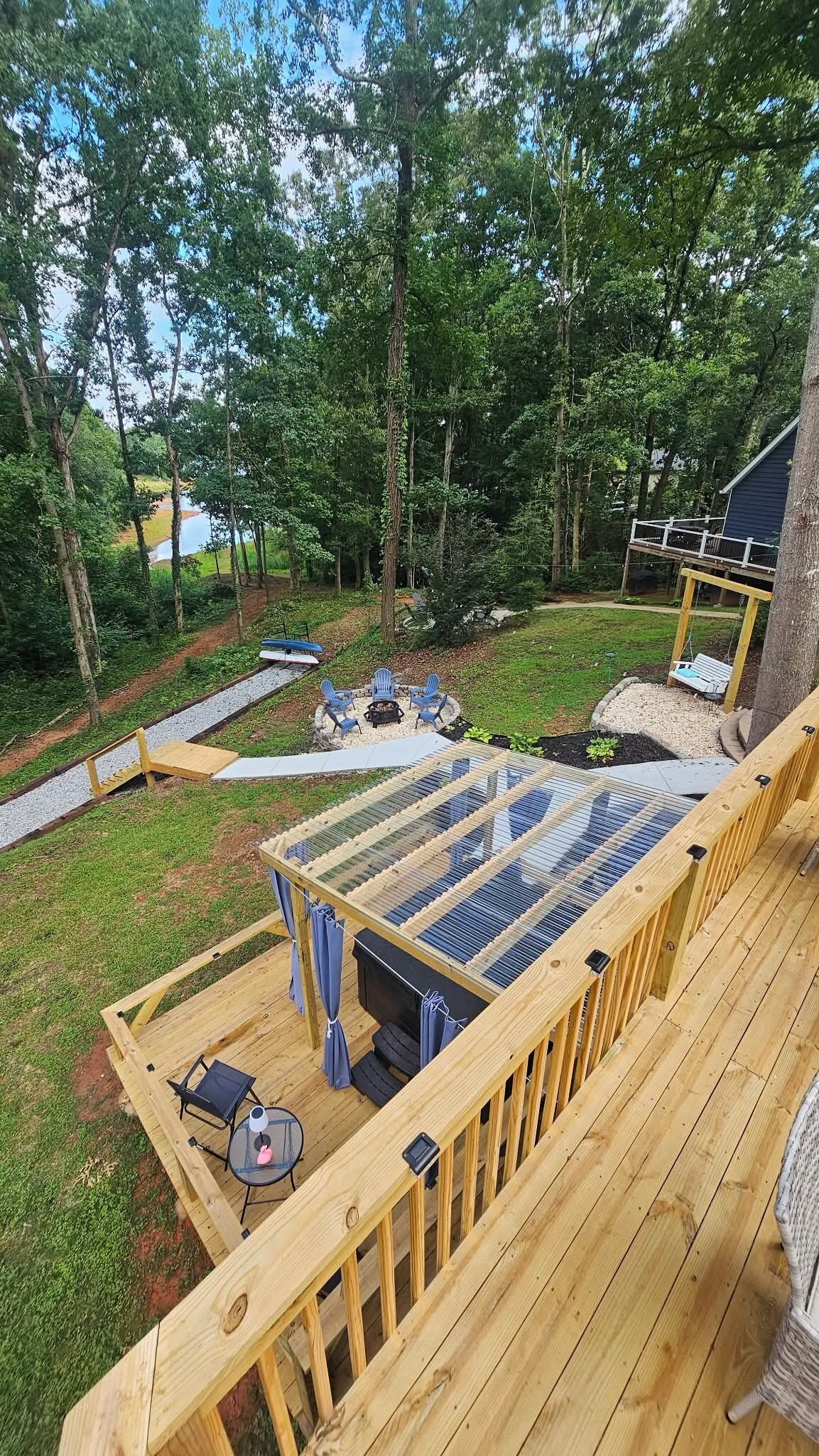 A wooden deck with a fire pit, outdoor seating, and a view of a forested area.