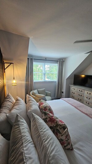 A bedroom with a bed, pillows, a dresser, a television, and a window with curtains. - The Cove at Portman, near Clemson. (Anderson)