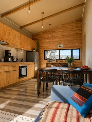 Une cuisine moderne avec des meubles en bois, un coin repas comprenant une table et des chaises, et une grande fenêtre offrant une vue dégagée.