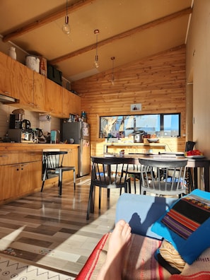 Une cuisine chaleureuse avec des meubles en bois, un coin repas avec des chaises et une grande fenêtre.