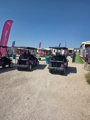 A gravel parking area with golf carts and flags. - Comfortable Mobile Home for 6 People (Veuzain-sur-Loire)