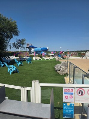 A pool area with lounge chairs, a water slide, and a sign indicating a swimming area. - Comfortable Mobile Home for 6 People (Veuzain-sur-Loire)
