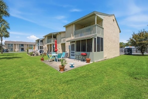 A residential building with a covered patio, outdoor seating, and a barbecue grill. - Gulf Highlands with a Golf Cart! (Panama City Beach)