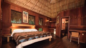 A wooden room with a bed, a chair, and a small table.