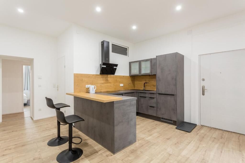 A modern kitchen with a central island, bar stools, and built-in cabinets.