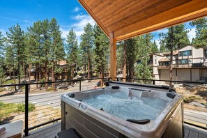 A hot tub on a wooden deck with a view of pine trees and buildings in the background. - Sierra Luxe Retreat - Hot tub close to Stateline (Zephyr Cove)