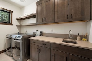 A modern kitchen with dark wooden cabinets, a stainless steel sink, and a built-in washing machine. - Sierra Luxe Retreat - Hot tub close to Stateline (Zephyr Cove)
