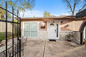 Ein Wohnhaus mit Garage, Eingangstür, Steinmauer und einer Terrasse mit Tisch und Stühlen.
