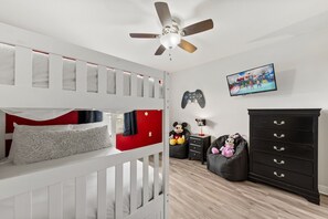A bedroom with a bunk bed, a ceiling fan, a gaming console, a television, and a dresser. - 1583 Moon Valley Drive (Davenport)