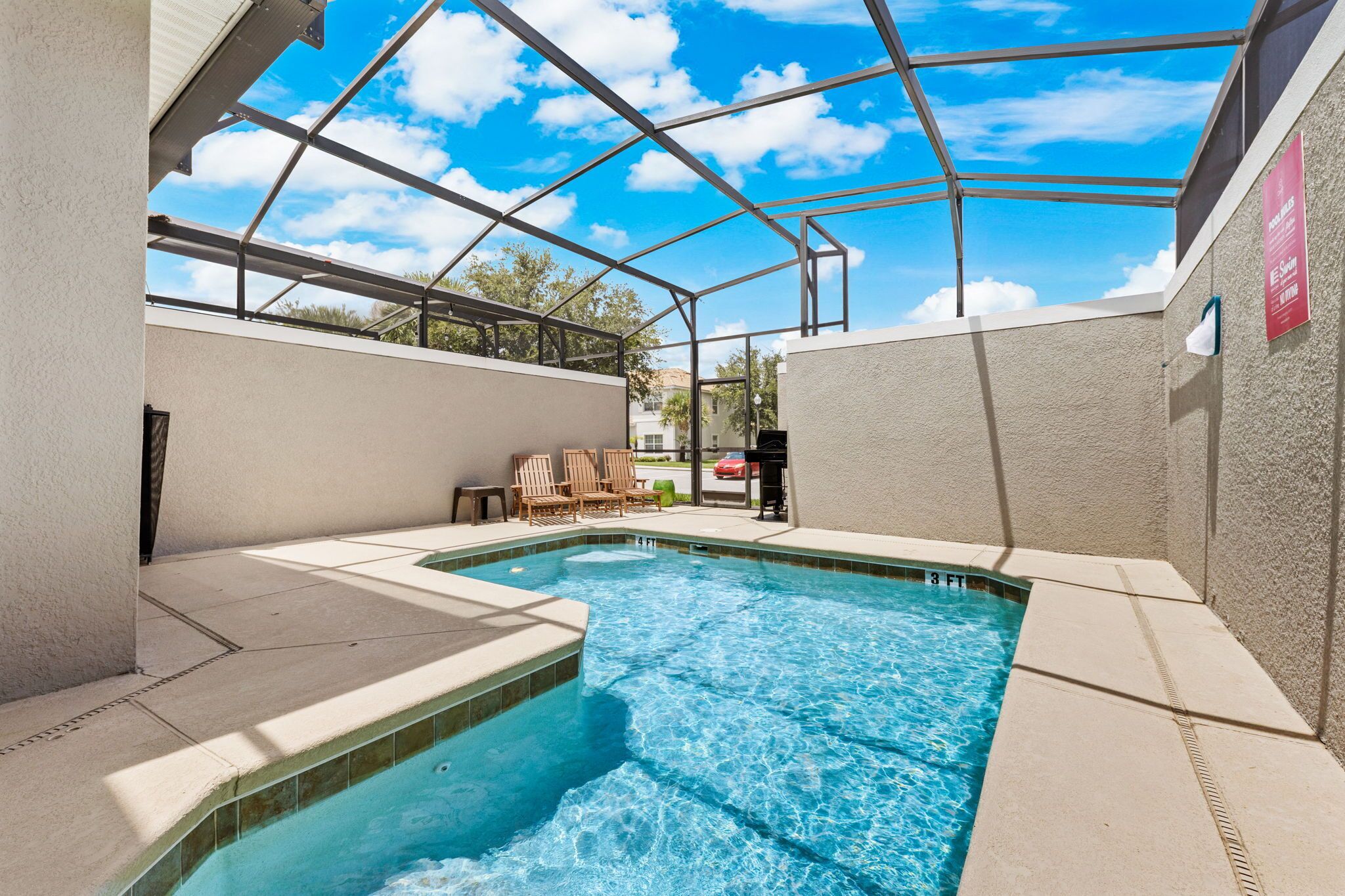 A swimming pool with a glass ceiling, surrounded by lounge chairs and a barbecue grill.