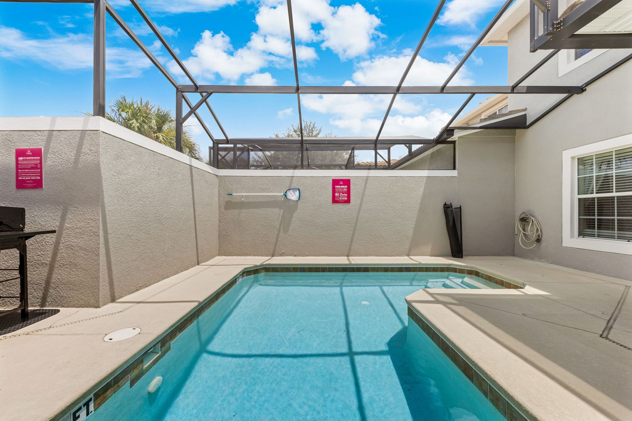 Una piscina con area coperta, una finestra e un cartello con le regole della piscina.