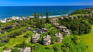 A coastal resort with multiple bungalow-style buildings, a parking area, and a view of the ocean.