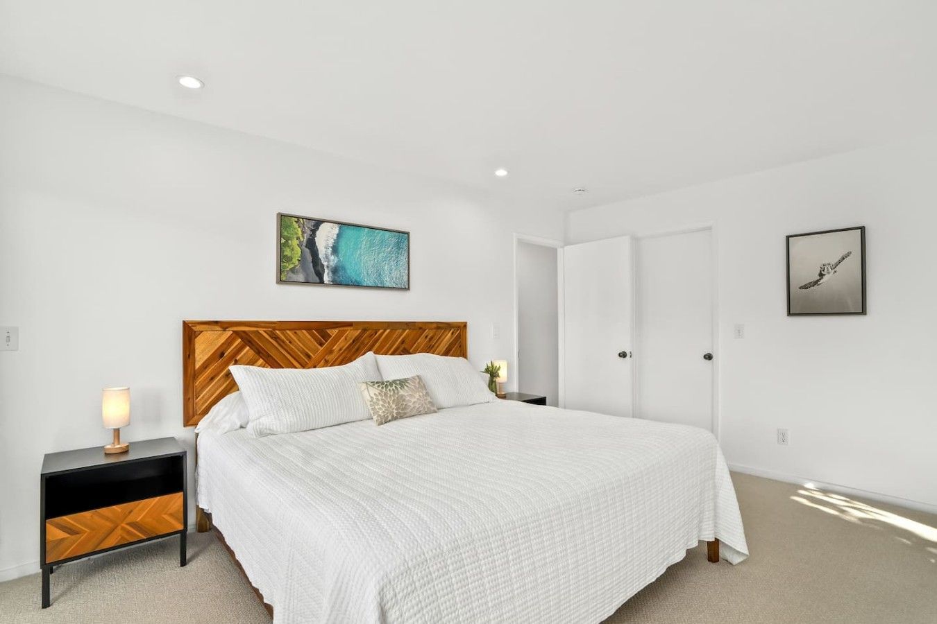 Une chambre à coucher avec un lit, une table de chevet, un tableau accroché au mur et une porte.