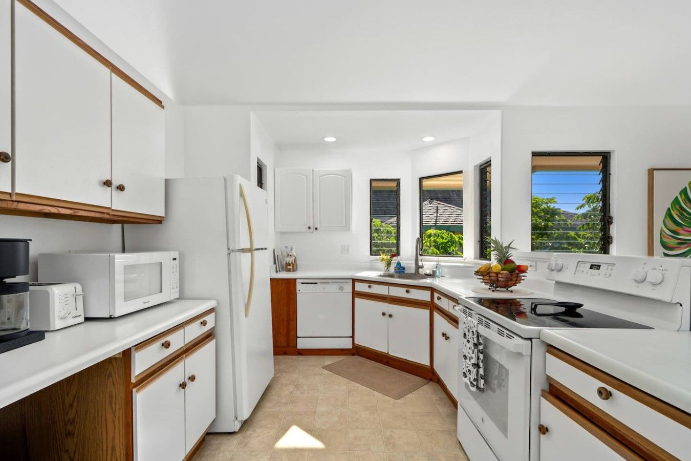 A compact kitchen with white cabinets, a microwave, a refrigerator, and a stove.
