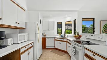 A compact kitchen with white cabinets, a microwave, a refrigerator, and a stove.