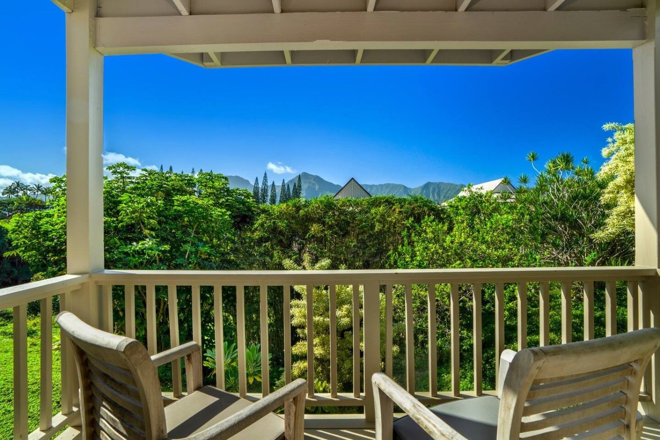 Un espace extérieur abrité, doté de chaises en bois et offrant une vue sur les montagnes et la verdure.