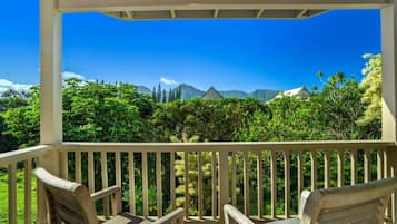A covered outdoor area with wooden chairs and a view of mountains and greenery.