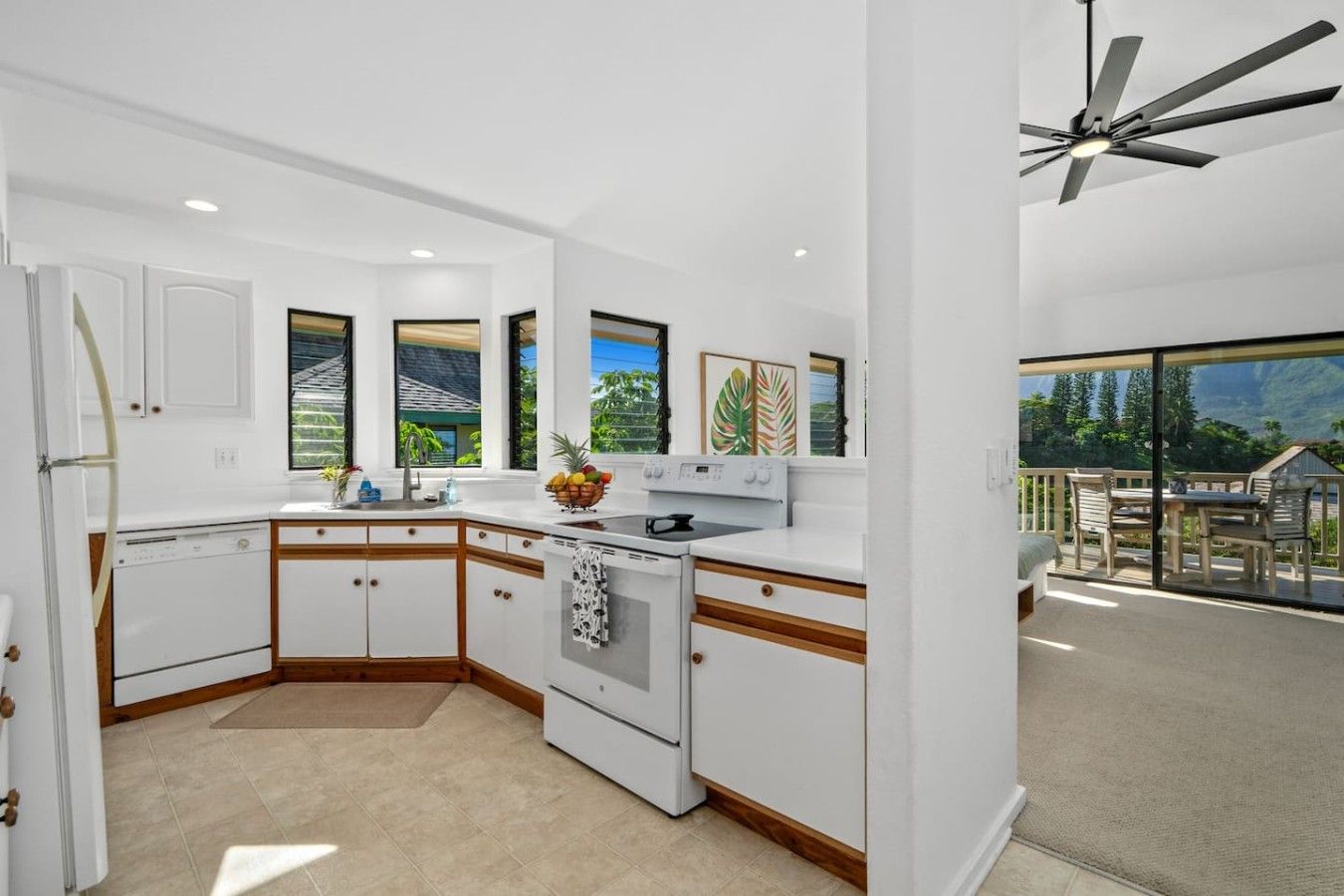 A modern kitchen with white cabinetry, a built-in oven, and a large window offering a view of the outdoors.