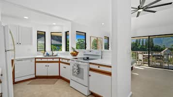 A modern kitchen with white cabinetry, a built-in oven, and a large window offering a view of the outdoors.