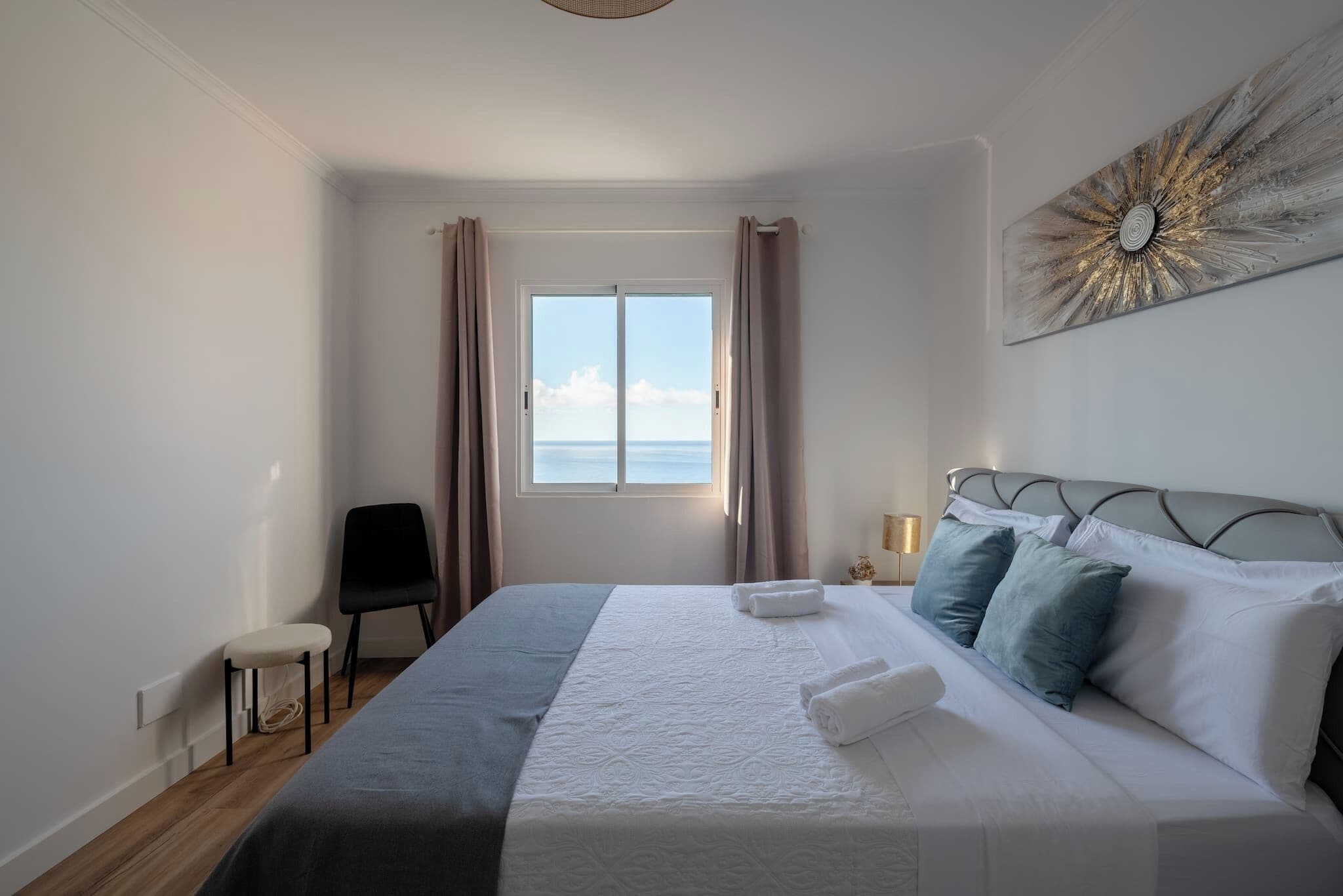 Een hotelkamer met een groot bed, een stoel, een bureau en een raam met gordijnen.