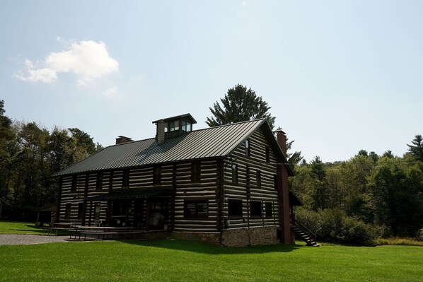 A log cabin with a chimney, a porch, and a staircase leading to the entrance.