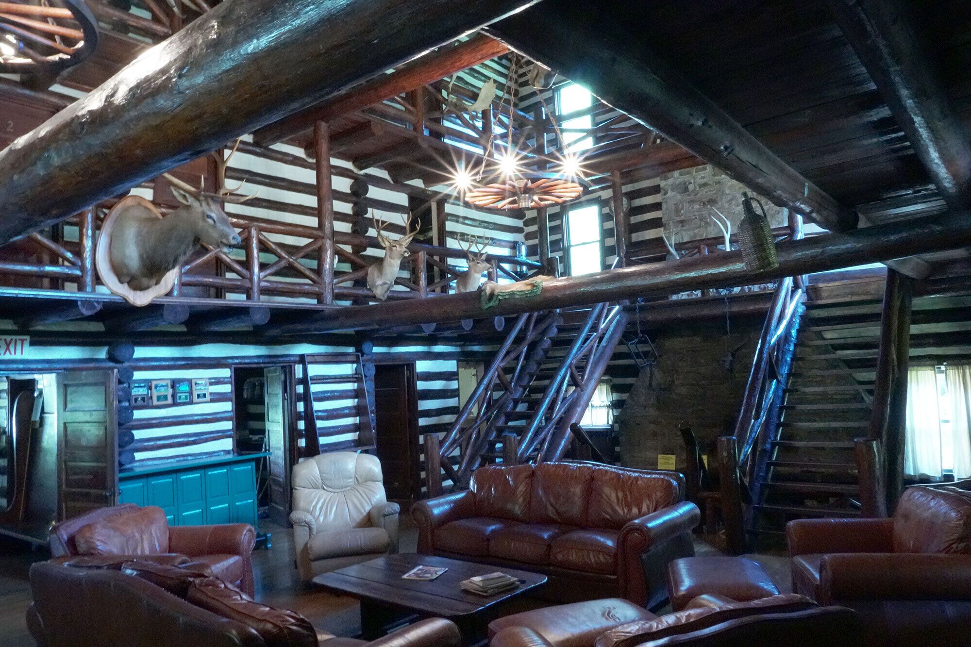 Un intérieur rustique avec des poutres en bois, des meubles en cuir et des bois de cerf fixés au plafond.