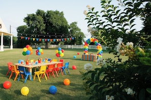 An outdoor party setup with a table, chairs, and a balloon arch.