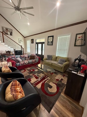 A living room with a sofa, armchairs, a coffee table, and a TV stand.