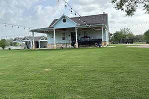 A house with a porch, a black truck parked in front, and a grassy yard.