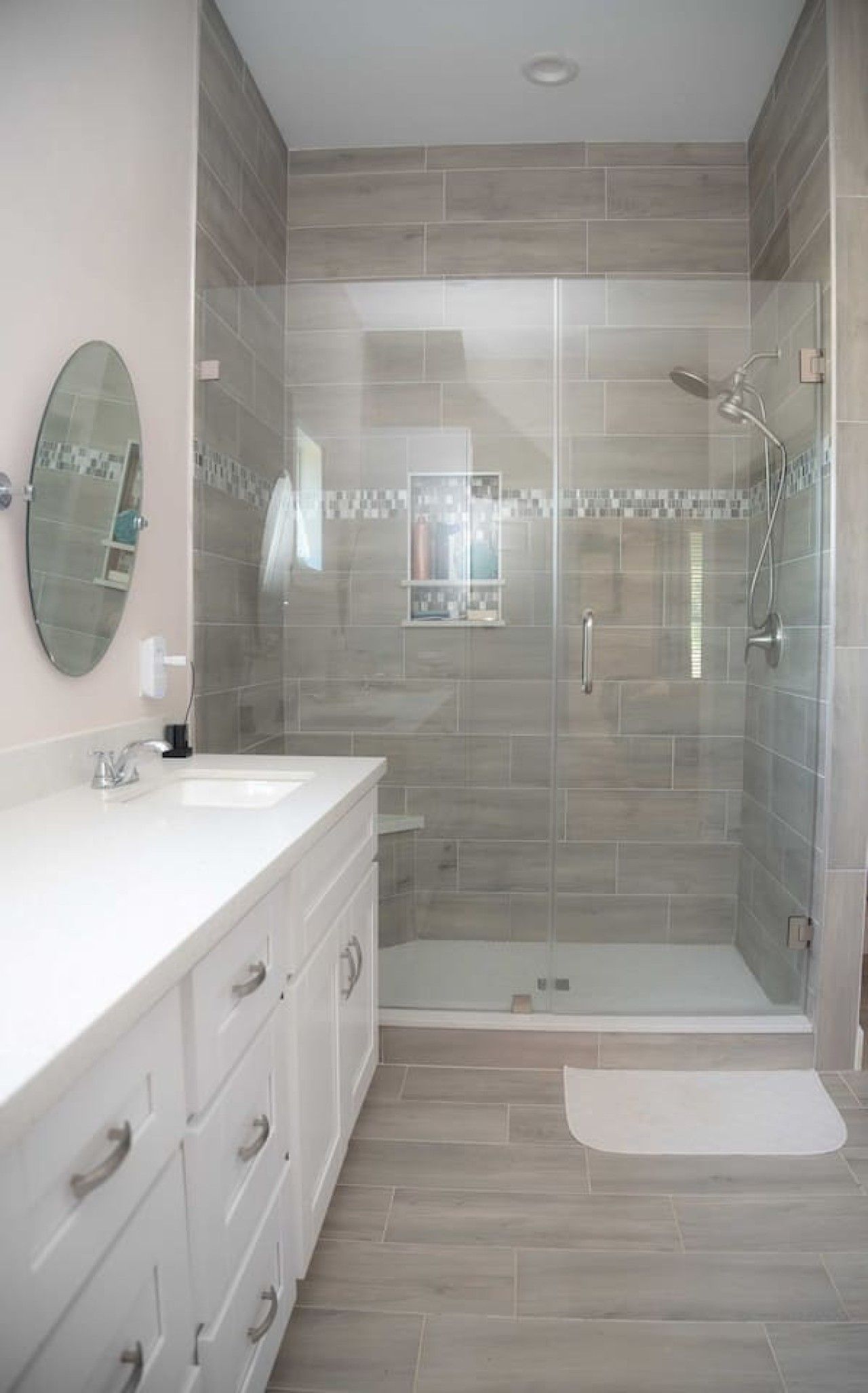A modern bathroom with a glass-enclosed shower, a large mirror, and a white vanity.