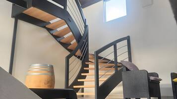 Un interior moderno con una escalera de caracol, un barril de madera y un sofá.