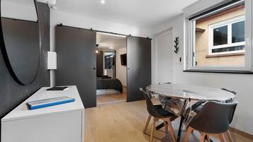 Ein modernes Interieur mit einem Esstisch, Stühlen, einem Bett und einem Fenster.