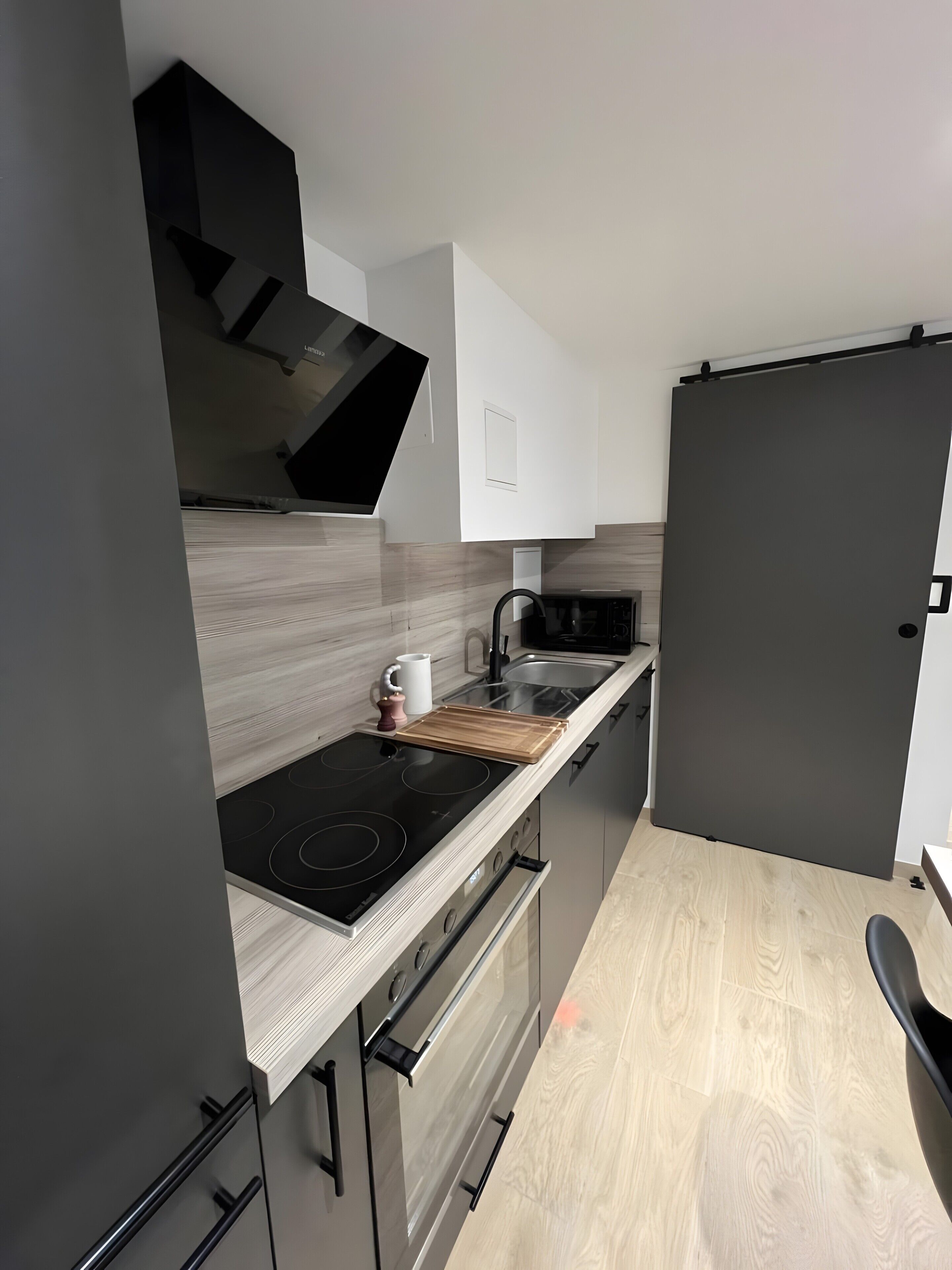 Eine moderne Küche mit einer schwarzen Induktionskochplatte, einer Mikrowelle und einem Holztisch.