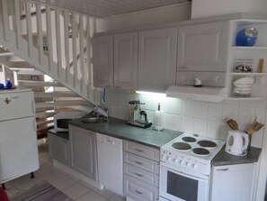 A kitchen with white cabinets, a stove, and a microwave. - Peuranpolku B | Spacious 2BR Chalet with Sauna (Ruka)