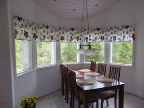 Ein Essbereich mit einem Holztisch, Stühlen und einem Fenster mit floralem Vorhang.