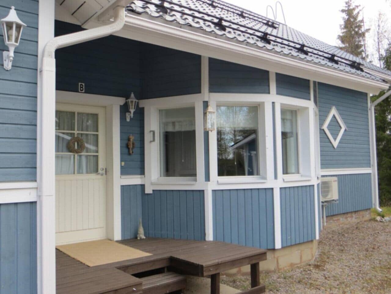 A blue house with a porch, a door, and a window.