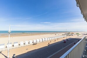 A beach view with a promenade, beach huts, and a clear sky. - 1 bedroom accommodation in Koksijde (Koksijde)