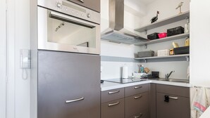 A modern kitchen with a built-in refrigerator, a microwave, and a stove. There are cabinets with handles and a countertop with a sink. - 1 bedroom accommodation in Koksijde (Koksijde)