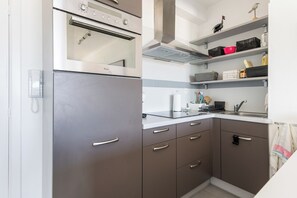 Uma cozinha moderna com geladeira embutida, micro-ondas e fogão. Há armários com puxadores e uma bancada com pia.